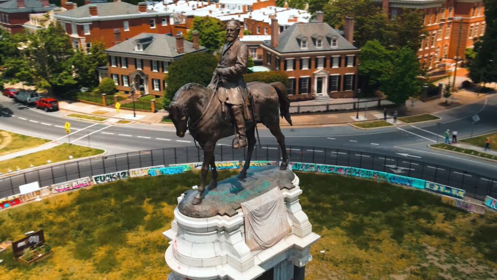A monument of a historical figure on horseback, encircled by graffiti-covered barriers