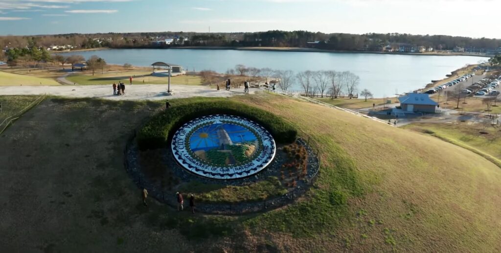 An aerial view of a park with a decorative city emblem and a lake