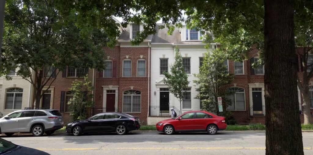 Row houses on a tree-lined street with parked cars